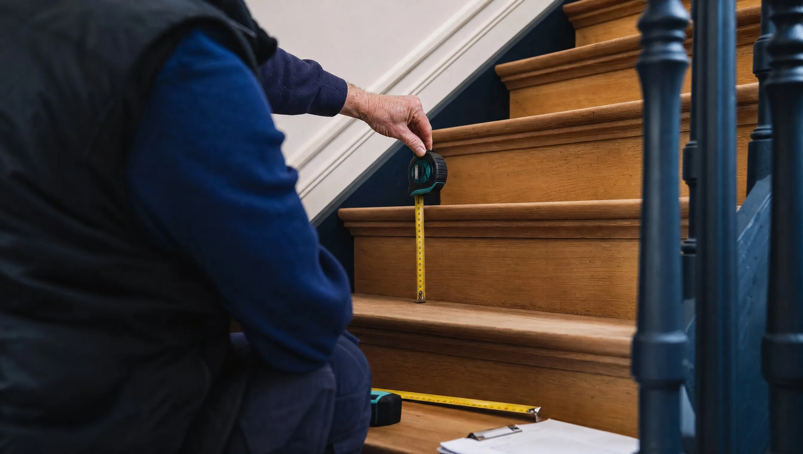 expert measuring riser height and tread depth of an interior staircase
