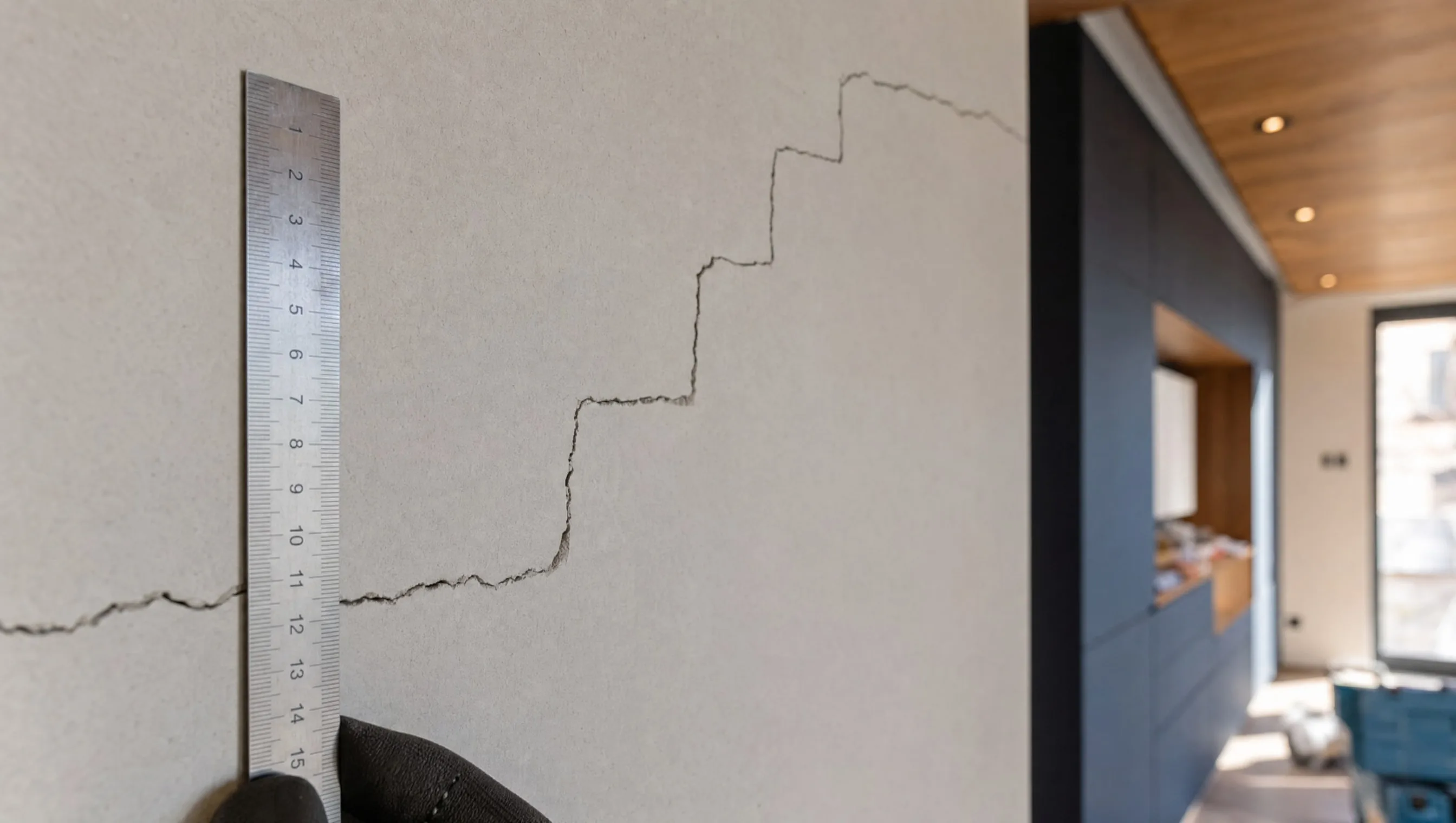 Metal ruler placed next to a step-shaped wall crack, new house Liège, April 2026